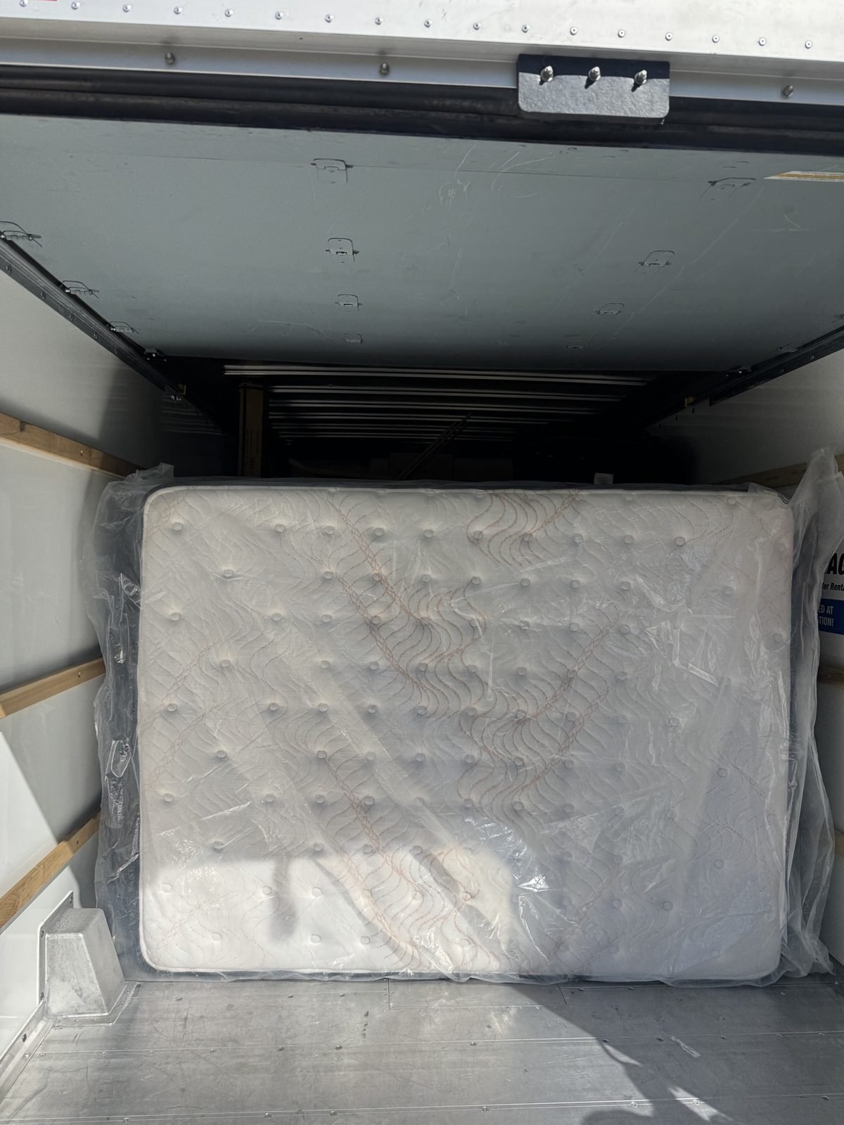 A mattress carefully wrapped in plastic inside a moving truck