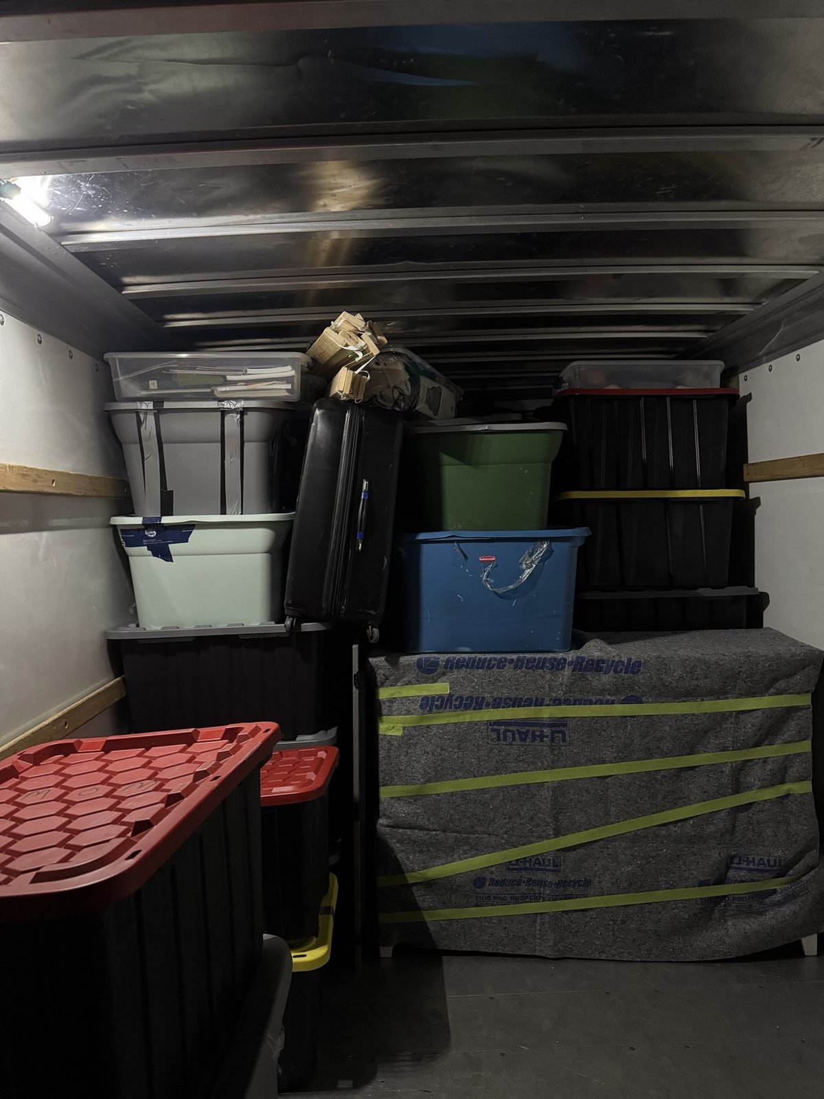 Storage bins, a suitcase and padded furniture loaded inside a moving truck